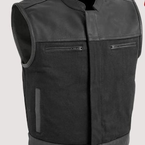 May include: A black leather and fabric vest with a stand-up collar. The vest features a combination of black leather and fabric panels, with two zipped pockets on the chest. The vest has a classic, timeless design.