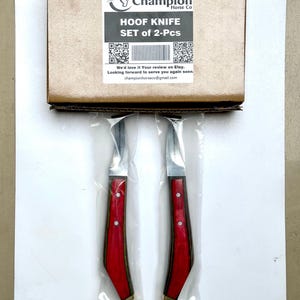 Pu&ograve; includere: Un set di due coltelli per zoccoli, ciascuno con un manico in legno rosso e una lama argentata, confezionati in plastica trasparente. I coltelli sono di Champion Horse Co. La scatola sopra i coltelli riporta la scritta "HOOF KNIFE SET of 2-Pcs".