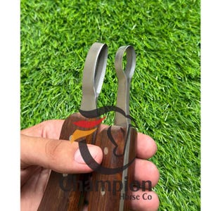 May include: Two hoof knives with dark brown wooden handles and silver-colored metal blades. One blade is curved into a loop shape, while the other is a standard curved blade. The text Champion Horse Co is visible on the handle.