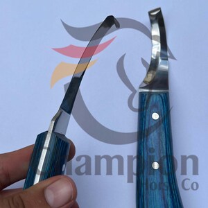 May include: Two hoof knives with blue and silver handles are displayed against a white background. The blades are curved and shiny. The handles have a blue wood grain pattern. One knife is held in a hand.
