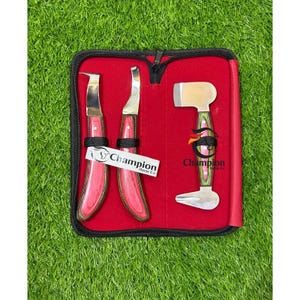Puede incluir: Un juego de tres cuchillos para cascos con mangos de madera roja y hojas de metal plateado, guardados en un estuche negro con cremallera e interior rojo. El logo de Champion Horse Co aparece impreso en el estuche y en una etiqueta blanca.