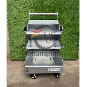 Puede incluir: Carro de aseo para caballos de metal plateado con tres estantes y un asa. El carro tiene el logotipo "Champion Horse Co" y está sobre ruedas para facilitar el transporte. El fondo es una pared verde.