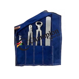 Puede incluir: Un estuche de herramientas de cuero azul que contiene herramientas de herrador. El juego incluye tenazas, un cuchillo para cascos y una lima. Las herramientas son de metal plateado. El texto "Champion Horse Co" es visible en el estuche.