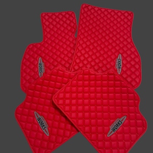 May include: Set of four red car floor mats with a quilted pattern. Each mat features the text "JOHN COOPER WORKS" in a silver and red emblem.
