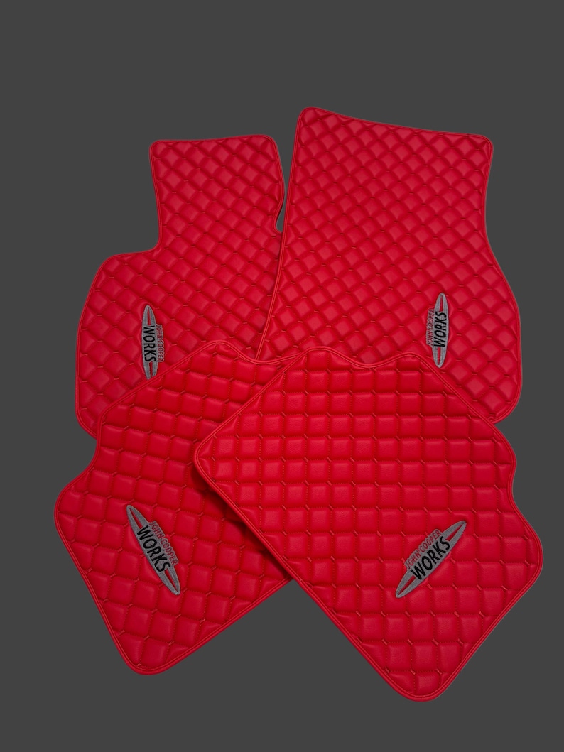 May include: Set of four red car floor mats with a quilted pattern. Each mat features the text "JOHN COOPER WORKS" in a silver and red emblem.