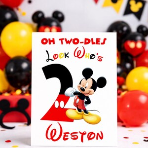 May include: A birthday card featuring Mickey Mouse with the text "OH TWO-DLES Look Who's 2 Weston" in red and black. The card is surrounded by red, yellow, and black balloons, and a Mickey Mouse-themed banner.