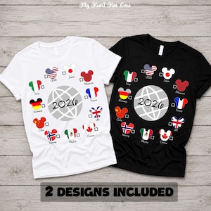 Könnte beinhalten: Ein weißes und ein schwarzes Kurzarm-T-Shirt, beide mit einer zentralen Grafik eines Globus und dem Text 2026. Um den Globus herum befinden sich mehrere Mickey-Mouse-förmige Symbole, die jeweils mit einer Nationalflagge gefüllt sind.