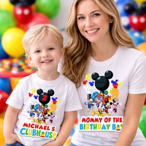 May include: Two white t-shirts featuring a colorful graphic of Mickey Mouse and friends. The smaller shirt displays the text "MICHAEL'S CLUBHOUSE" with a red number two, while the larger shirt displays the text "MOMMY OF THE BIRTHDAY BOY".