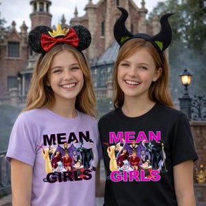 K&ouml;nnte beinhalten: Zwei l&auml;chelnde Personen tragen Themen-Stirnb&auml;nder und T-Shirts. Einer tr&auml;gt ein Minnie-Mouse-Ohren-Stirnband mit roter Schleife, der andere ein schwarzes Horn-Stirnband. Die Shirts tragen die Aufschrift "MEAN GIRLS" mit einer Grafik von Disney-B&ouml;sewichten.