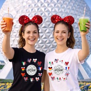 May include: Two women wearing red sequined Minnie Mouse ears and t-shirts with a 2026 graphic and flags of different countries. One shirt is black, the other white. Each woman holds a beverage in a clear cup.