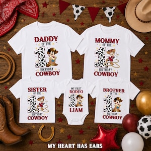 Op de afbeelding: Een set witte t-shirts en een babyrompertje met een koeienprint nummer één, tekenfilmmuizen in cowboykleding en tekst waaronder Daddy, Mommy, Sister, Brother en My First Rodeo Liam, voor een cowboythema voor een eerste verjaardag.
