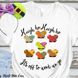 May include: White t-shirt with a graphic of seven dwarf-themed mouse ears and the text "Heigh ho Heigh ho It's off to work we go." A green and purple sequined bow headband is visible on the left. The shirt is white.