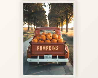 May include: A framed print featuring a vintage red pickup truck filled with orange pumpkins. The truck bed reads "PUMPKINS" in a bold font. The background shows a tree-lined road, evoking a fall harvest theme.