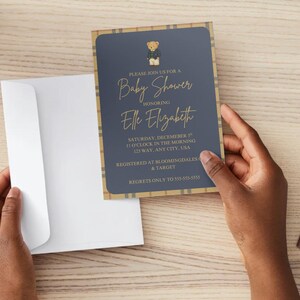 May include: A baby shower invitation with a navy blue background and gold text. The invitation features a teddy bear illustration and a plaid border. The text reads "Please join us for a Baby Shower honoring Elle Elizabeth."