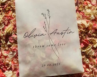 May include: A white paper packet with the text "Olivia Austin" in cursive, with the words "throw some love" below. A floral illustration and the date "29.08.2025" are also printed on the packet. The packet is surrounded by dried flower petals.