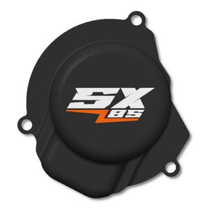 Puede incluir: Cubierta negra del motor de la motocicleta con el texto blanco y naranja "SX BS". La cubierta tiene un centro circular y tres orificios de montaje. La forma general es irregular.