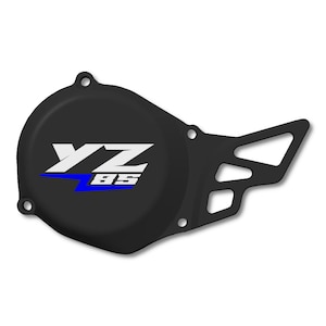 Peut inclure: Cache moteur de moto noir avec le texte blanc et bleu "YZ BS". Le couvercle a une forme unique avec une section découpée sur le côté droit et plusieurs trous de montage.