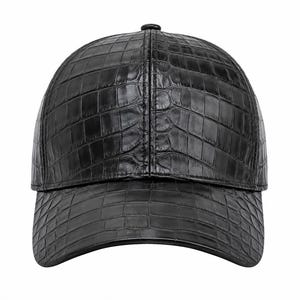 May include: A black baseball cap featuring a textured, embossed crocodile skin pattern across the entire surface, including the crown and the curved brim, with a small button at the top centre and visible stitching along the panels.