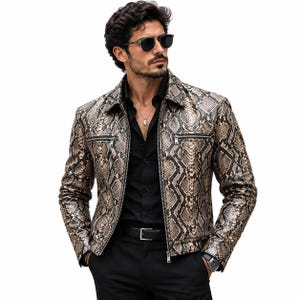 May include: A long-sleeved jacket featuring a brown and black snakeskin pattern, a pointed collar, and a full-length front zip. The garment includes two horizontal zipped chest pockets and is worn over a black button-down shirt and black trousers.