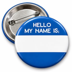 Op de afbeelding: Een ronde blauw-witte button met de tekst HELLO MY NAME IS: in witte hoofdletters aan de bovenzijde. Het midden van de button heeft een brede horizontale witte strook om een naam op te schrijven, met een metalen speld aan de achterkant.