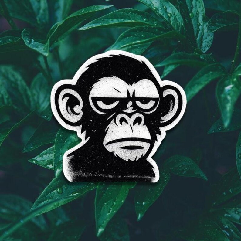 May include: A black and white sticker featuring a stylized monkey face with a serious expression. The monkey has a white outline and is set against a background of green leaves.