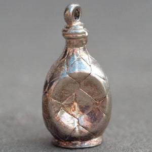 May include: Silver charm in the shape of a bottle with a diamond pattern.