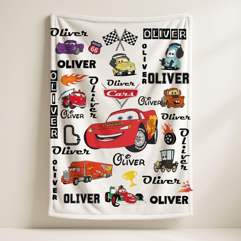 May include: A white fleece blanket featuring a repeating pattern of Disney Cars characters including Lightning McQueen, Mater, and a fire truck. The design includes the name Oliver in various fonts, checkered flags, a trophy, and Route 66 signs.