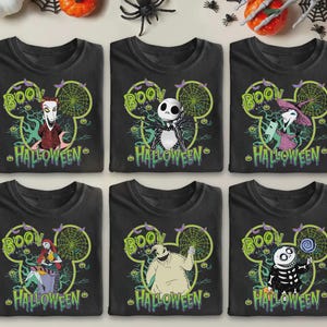 May include: Six black t-shirts with Halloween-themed graphics. Each shirt features a different character from The Nightmare Before Christmas, the word "BOO!" and the word "HALLOWEEN" in green. The designs are set within a Mickey Mouse head shape.