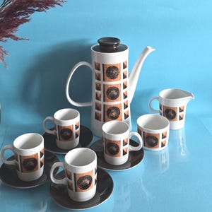 May include: A ceramic coffee set featuring a tall coffee pot with a brown lid, a creamer, and four cups with matching saucers. Each piece is white with a repeating geometric pattern of brown circles and orange triangles on a textured background.