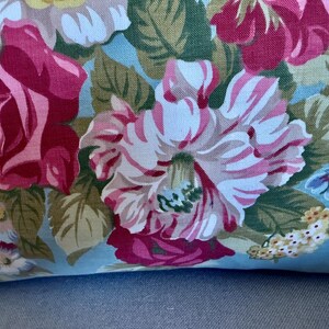 Puede incluir: Una tela azul con un patr&oacute;n floral con rosas rosas, blancas y verdes. La tela tiene un tacto suave y texturizado.
