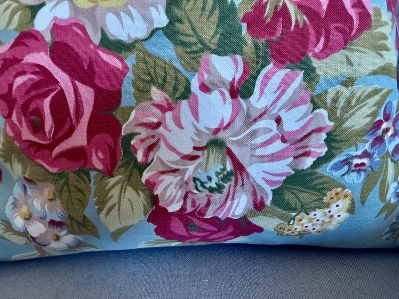 Puede incluir: Una tela azul con un patr&oacute;n floral con rosas rosas, blancas y verdes. La tela tiene un tacto suave y texturizado.