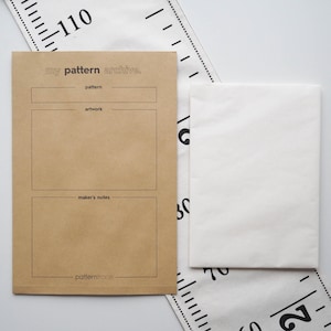 May include: A brown paper pattern archive envelope with the text "my pattern archive." and sections for pattern, artwork, and maker's notes. A white paper envelope and a measuring tape are also visible.