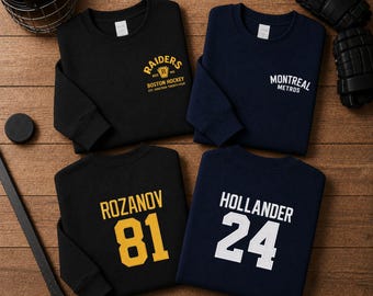 May include: Four long-sleeve crewneck sweatshirts in black and navy blue. One black sweatshirt features yellow text reading RAIDERS BOSTON HOCKEY EST. NINETEEN TWENTY-FOUR. One navy sweatshirt says MONTREAL METROS. Others feature names ROZANOV 81 and HOLLANDER 24.