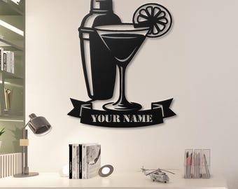 May include: Black metal wall art featuring a cocktail shaker, martini glass with a lemon slice, and a banner with the text "YOUR NAME". The design is a silhouette, suitable for a bar or kitchen.