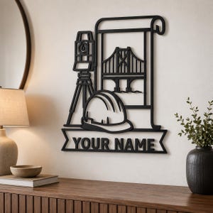 May include: A black wall-mounted sign featuring a laser level on a tripod, a bridge illustration on a scroll, and a hard hat. Below these elements is a banner with the text YOUR NAME in bold, capital letters, creating a custom display.