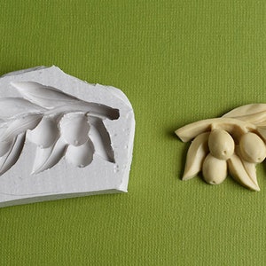 Può includere: Uno stampo in silicone bianco e una fusione in resina beige di un ramo di ulivo con foglie e olive.