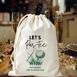 May include: A white drawstring bag with the text "LET'S Par-Tee" in black script, along with a green golf ball and tee graphic. The bag also features the text "PUTT MASTERS GOLF & COUNTRY CLUB" in green. Two champagne flutes are in the background.