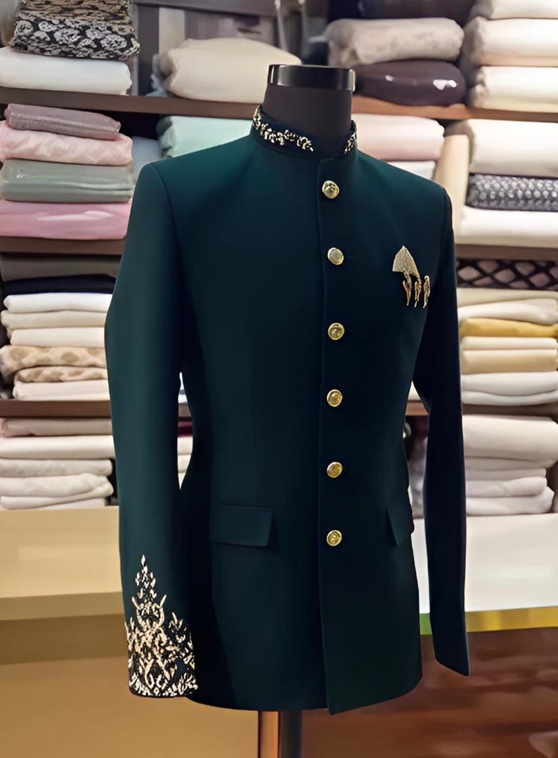 Puede incluir: Chaqueta verde oscuro con cuello mandar&iacute;n y botones dorados. La chaqueta presenta bordados dorados en los pu&ntilde;os y un broche decorativo dorado en el pecho. La chaqueta se exhibe en un maniqu&iacute;.