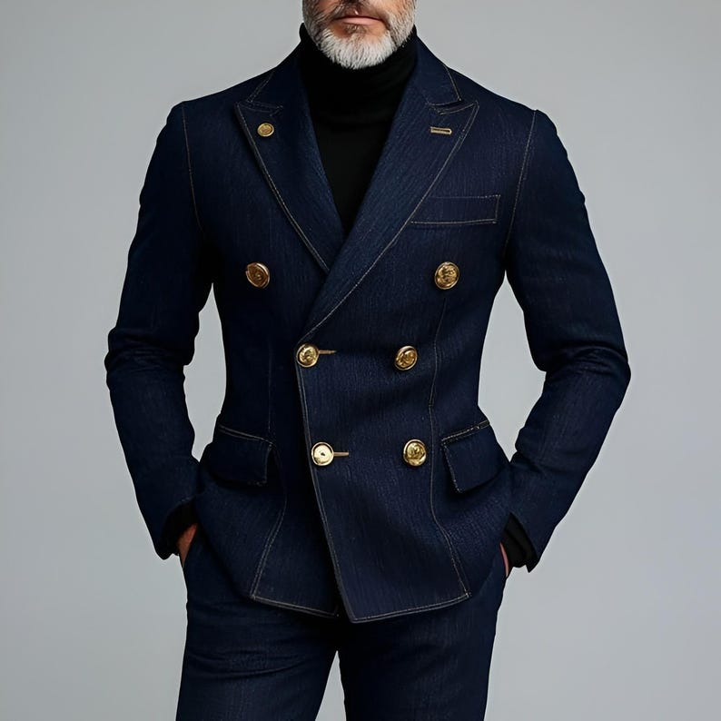 Pode incluir: Um blazer de ganga azul escuro com bot&otilde;es dourados. O blazer tem um corte sob medida e costuras vis&iacute;veis. O casaco faz parte de um fato, com cal&ccedil;as de ganga azul escuro a condizer.