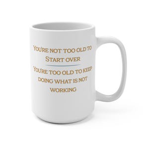 May include: White ceramic mug with a curved handle. The mug features the text "YOU'RE NOT TOO OLD TO START OVER YOU'RE TOO OLD TO KEEP DOING WHAT IS NOT WORKING" in a brown font. The mug is a standard size.