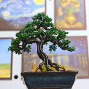Bonsai artesanal de tronco preto e madeira verde, escultura de bonsai em arame dentro de vaso de cerâmica.