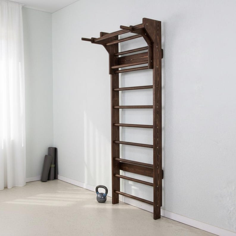 Puede incluir: Una espaldera de madera de color marr&oacute;n oscuro montada en la pared, que cuenta con una serie de pelda&ntilde;os horizontales y una barra de dominadas integrada en la parte superior. La estructura est&aacute; fijada verticalmente para ejercicios.