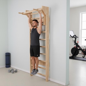 Puede incluir: Una espaldera de madera montada en la pared que cuenta con una serie de pelda&ntilde;os horizontales y una barra de dominadas superior extendida. La estructura est&aacute; fabricada en madera natural de color claro y fijada a una pared vertical.