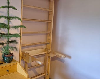 Könnte beinhalten: Ein an der Wand montiertes Klettergerüst aus hellem Holz mit einer vertikalen Leiter mit horizontalen Sprossen und einem verlängerten oberen Teil, der nach außen gebogen ist. Die Struktur enthält einen abnehmbaren horizontalen Aufsatz auf mittlerer Höhe.