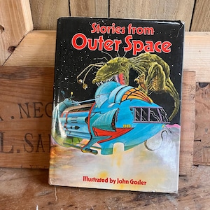 May include: Vintage book titled "Stories from Outer Space." The cover shows a spaceship, a green alien, and the title in red against a black starry background. The illustration is by John Gosler. A retro science fiction book.
