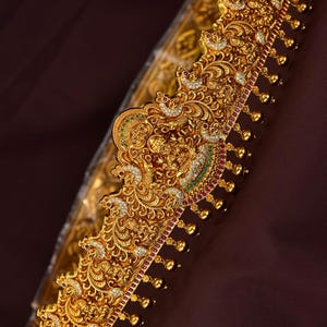 May include: Ornate gold-colored belt with intricate filigree and jewel detailing. The belt features a central design with a figure, surrounded by floral and peacock motifs. The text "STYLE825/ ADULT-BELT" is visible in the image.