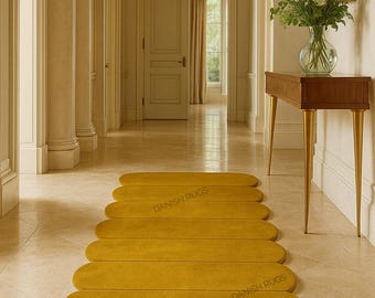以下が含まれることがあります： 廊下に配置されたマスタードイエローのランナーラグ。 「DANISH RUGS」とラベルされたラグは、丸みを帯びた細長い形状をしています。 廊下にはシャンデリア、木製のコンソールテーブル、花瓶に入った花があります。