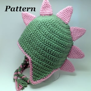 May include: Green and pink crocheted hat with a pointed top and a long tail. The hat has a pattern of spikes around the top.