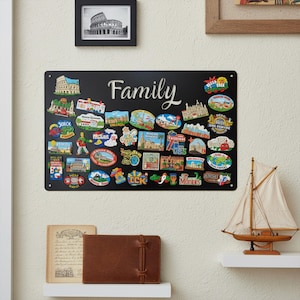 May include: A black metal sign with the word "Family" in white script, adorned with colourful souvenir magnets. The magnets showcase various landmarks and locations. A framed photo of the Colosseum is above the sign.