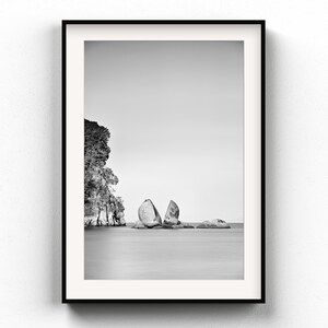 Könnte beinhalten: Schwarz-Weiß-Druck eines gerahmten Meerespanoramas. Das Bild zeigt eine Felsformation im Wasser, mit einer Klippe auf der linken Seite. Der Himmel ist bedeckt. Der Druck wird an einer weißen Wand gezeigt.